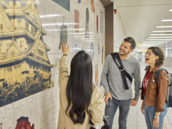 Host pointing out hidden signage to curious travelers on a quiet street Host pointing out hidden signage to curious travelers on a quiet street