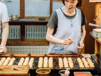 Elderly woman preparing takoyaki at a small neighborhood stall Elderly woman preparing takoyaki at a small neighborhood stall