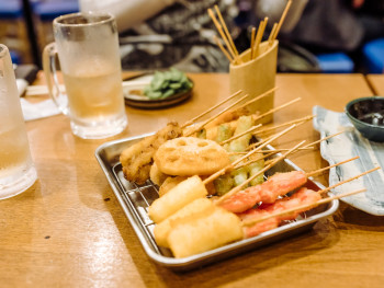 Small traditional kushikatsu restaurant with customers eating at the counter.