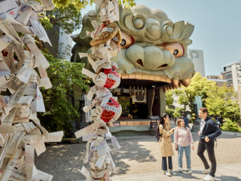 The distinctive lion head structure at Namba Yasaka Shrine with traditional architecture and modern city buildings in the background The distinctive lion head structure at Namba Yasaka Shrine with traditional architecture and modern city buildings in the background