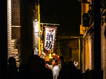 A friendly local host gesturing animatedly while walking with guests through the narrow, lantern-lit streets of Ura Namba. Image by Kilian Murphy on Unsplash. A friendly local host gesturing animatedly while walking with guests through the narrow, lantern-lit streets of Ura Namba. Image by Kilian Murphy on Unsplash.