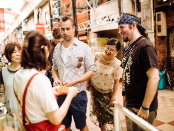 Tour guide explaining food preparation at a traditional stall Tour guide explaining food preparation at a traditional stall