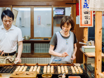 Street vendor expertly making takoyaki with flying batter and quick movements Street vendor expertly making takoyaki with flying batter and quick movements