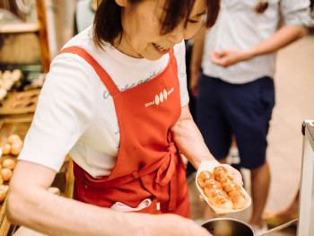 Chef preparing takoyaki at street stall with customers watching Chef preparing takoyaki at street stall with customers watching