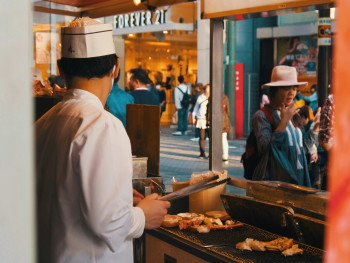 A street food vendor preparing hot food near Osaka Station, with commuters stopping for quick warming meals Photo by Nomadic Julien on Unsplash A street food vendor preparing hot food near Osaka Station, with commuters stopping for quick warming meals Photo by Nomadic Julien on Unsplash