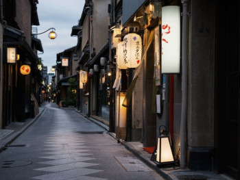 Narrow Sonezaki alley lined with small izakayas, warm light spilling from doorways. Narrow Sonezaki alley lined with small izakayas, warm light spilling from doorways.
