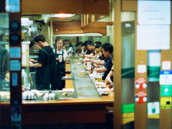Cooking class participants learning to make takoyaki, instructor demonstrating proper pan technique.Photo by kilo Cooking class participants learning to make takoyaki, instructor demonstrating proper pan technique.Photo by kilo