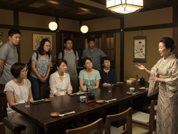 A guide demonstrating dining etiquette to guests at a traditional-style restaurant A guide demonstrating dining etiquette to guests at a traditional-style restaurant