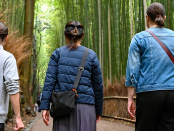 Towering bamboo stalks creating natural tunnel with filtered green light and people walking the shaded pathway. Towering bamboo stalks creating natural tunnel with filtered green light and people walking the shaded pathway.