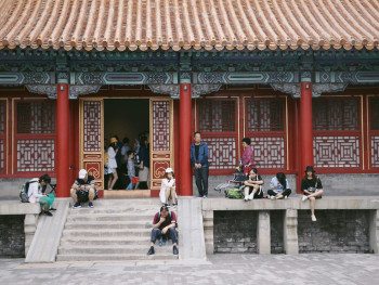 A quiet temple courtyard with children sitting on wooden steps, sketching in notebooks Photo by Emily Xie on Unsplash