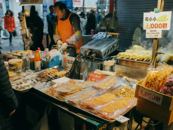 A traveler sampling street food at Nishiki Market, surrounded by colorful stalls and guided by a local Photo by Huy Phan on Unsplash A traveler sampling street food at Nishiki Market, surrounded by colorful stalls and guided by a local Photo by Huy Phan on Unsplash