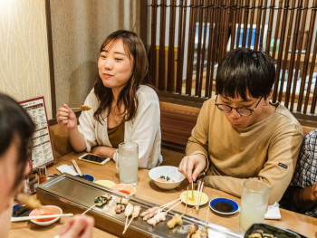 A small local izakaya with customers sitting at the counter and warm lighting A small local izakaya with customers sitting at the counter and warm lighting