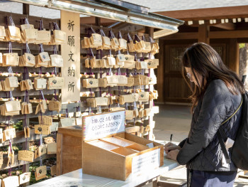 Guest writing a Ema board at Meiji Shrine Guest writing a Ema board at Meiji Shrine