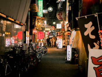 A narrow street illuminated with traditional lanterns, filled with the aromatic steam from various food stalls. A narrow street illuminated with traditional lanterns, filled with the aromatic steam from various food stalls.