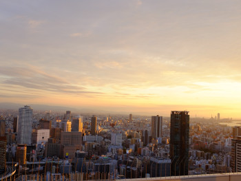 Sunset view of Osaka's skyline from the Umeda Sky Building's outdoor observation deck, with visitors silhouetted against the panoramic cityscape photo by 2560123289 on Shutterstock