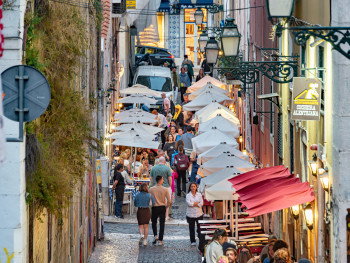 People drinking on narrow cobblestone streets at night by Jorge Franganillo via WikiCommons 