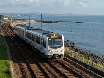 DART train running along the coast near Dublin Bay, offering scenic sea views