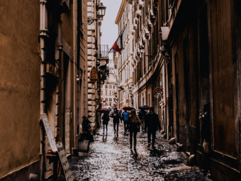 Person walking on wet Lisbon cobblestones with umbrellas