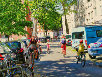 Children cycling safely on neighborhood bike path with parents Children cycling safely on neighborhood bike path with parents