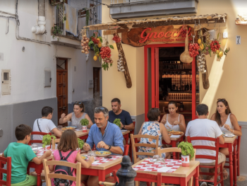 Family sharing traditional Italian food at a sunny outdoor restaurant Family sharing traditional Italian food at a sunny outdoor restaurant