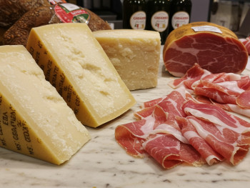 Parmigiano wedges and hand-sliced prosciutto at a small alimentari Parmigiano wedges and hand-sliced prosciutto at a small alimentari