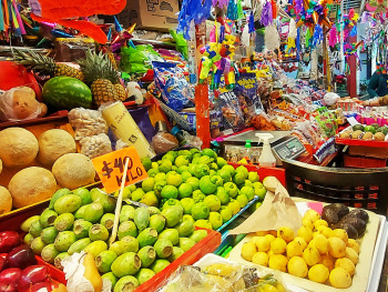 Fruit stalls with handwritten signs and shoppers