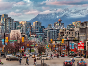 Street view of a busy Vancouver street with mountains in the distance Street view of a busy Vancouver street with mountains in the distance