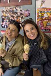 Two women enjoy ice cream at a bench inside a Japanese dessert store.
