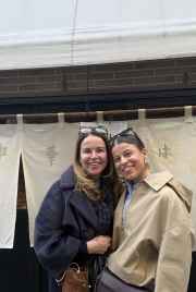 Two people standing in front of a restaurant with Japanese signage.