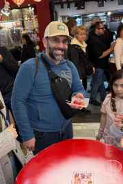 A family enjoys snacks at a table inside a busy Kyoto market area.