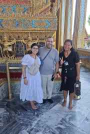 Three people standing in front of ornate architecture at the Grand Palace, Bangkok.
