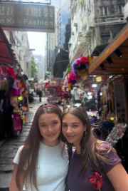 Tourists pausing for a smile amidst Hong Kong's bustling market lanes.