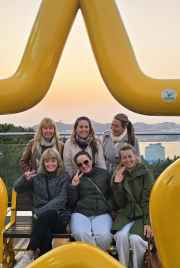 Friends laughing together as the sun sets over Busan's skyline.