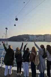 Tourists reaching for the sky as cable cars glide over Busan Bay.
