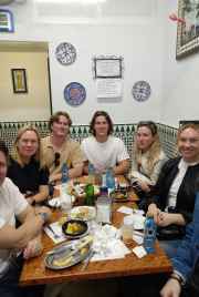 A group savoring traditional bites in a charming Seville corner.