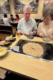 Steam rises from a sizzling okonomiyaki in Tokyo's cozy eatery.
