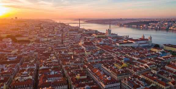 Aerial view of Lisbon's orange rooftops and the Tagus River at sunrise