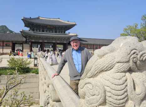 Man poses near carved stone figures at Gyeongbokgung Palace entrance.