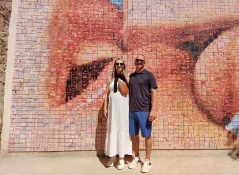 Two people stand in front of the 'El Beso' mural in Barcelona.