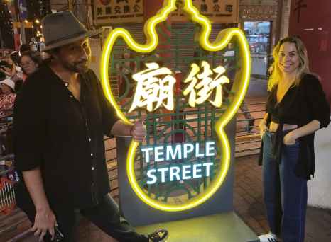 Neon sign reading 'Temple Street' with two people posing beside it in Hong Kong.
