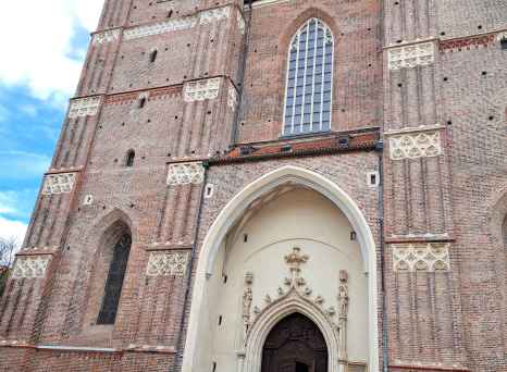 Facade of the Basilica di San Petronio in Munich with people walking outside.