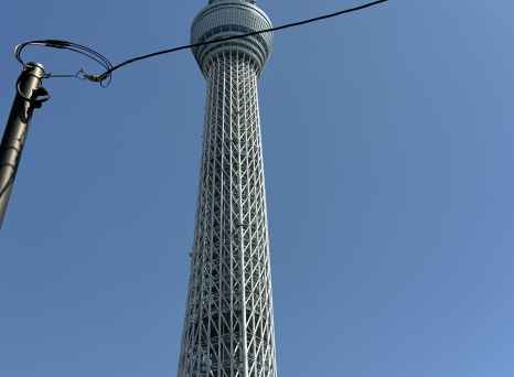 Upward perspective of Tokyo Skytree with a visible cable line.