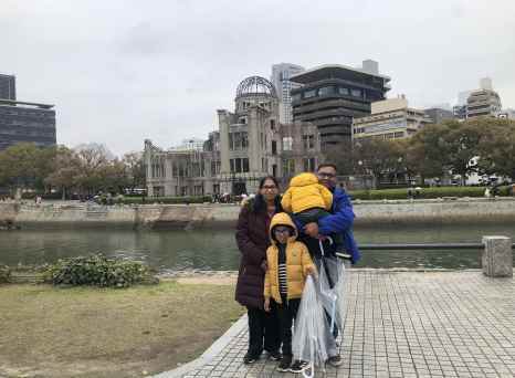 Group pictured with Hiroshima Peace Memorial and cityscape background.