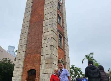 The historic Clock Tower in Hong Kong surrounded by pedestrians.
