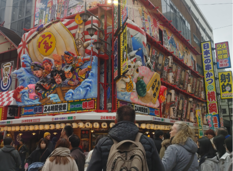 Street scene with people in front of Shinsekai district shopfront, Osaka, Japan.