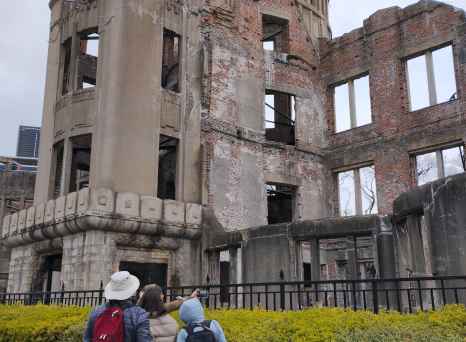 A view of the Atomic Bomb Dome in Hiroshima, Japan with visitors nearby.