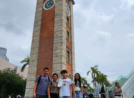 Group of people standing in front of the Tsim Sha Tsui Clock Tower in Hong Kong.