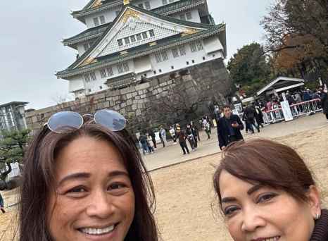 Two women taking a selfie in front of Osaka Castle.