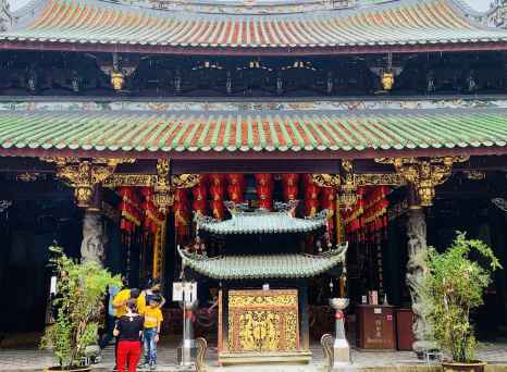 A family visits Thian Hock Keng Temple, showcasing intricate carvings and red lanterns.