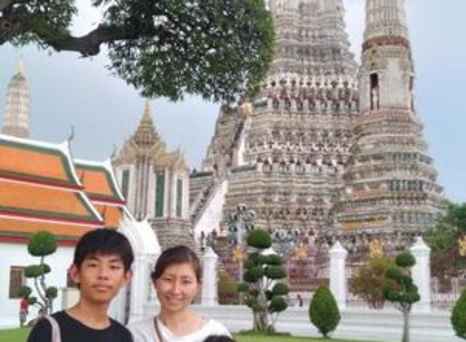 Three people stand in front of Wat Arun in Bangkok, Thailand.